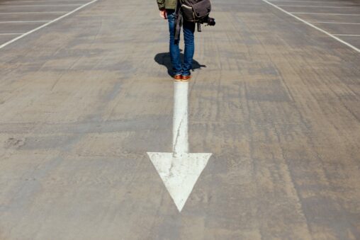 person standing on arrow on road